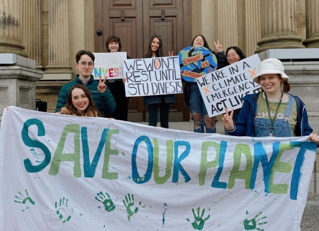 A group of protesters hold a sign that says “save our planet”