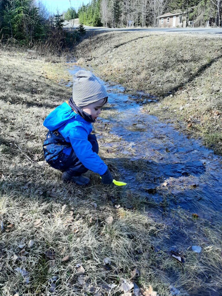 A young boy plays in a puddle 