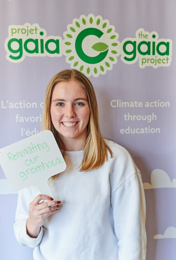 A teenager holds a sign, committing to renovating her greenhouse 