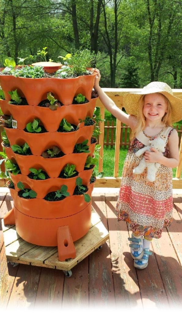 A child stands next to a Garden tower 2 freshly planted with sprouts
