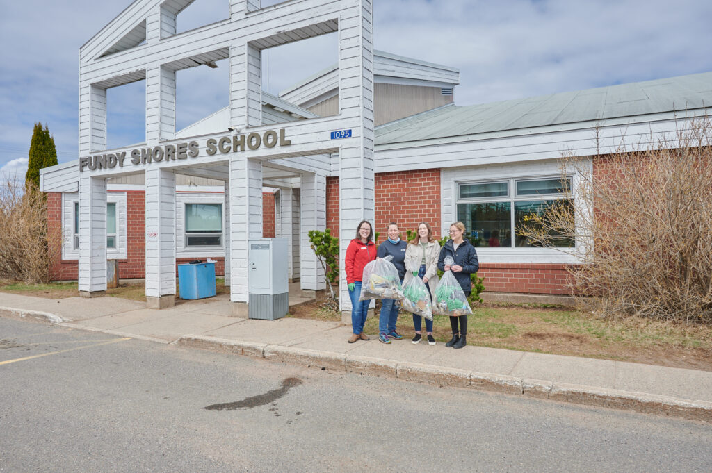 The Gaia Project and school facilitators stand outside the school entrance with the collected bags of waste