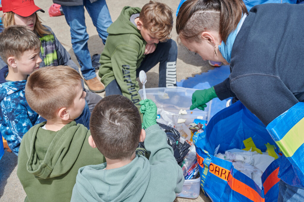 Guylaine starts quizzing the students about what belongs in each bin, and challenges them to sort through and organize the contents of each bag. The Gaia Project team hands out gloves, splits the students into small groups and the waste audit begins! 
