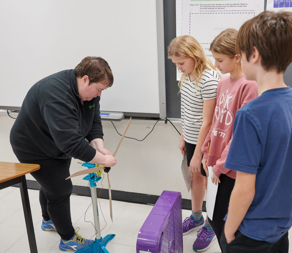 A Gaia staff uses a small wind turbine to teach a group of students about wind energy 
