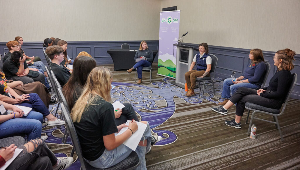 Three Green Expert panelists sit in front of a teenaged audience 