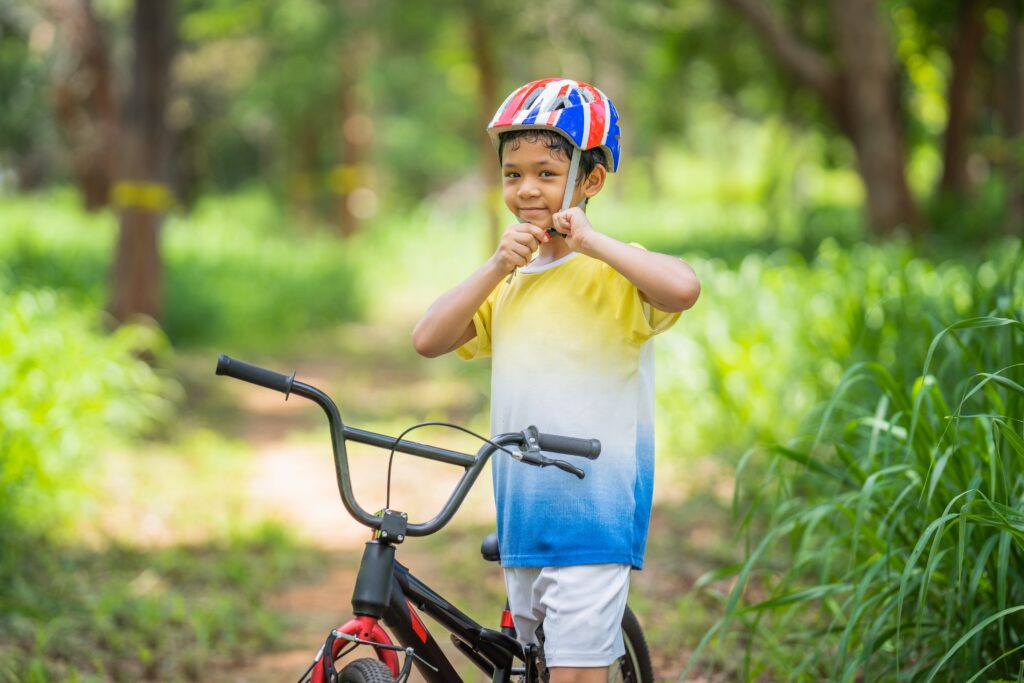 Un jeune garçon se tient debout à côté d’un vélo 