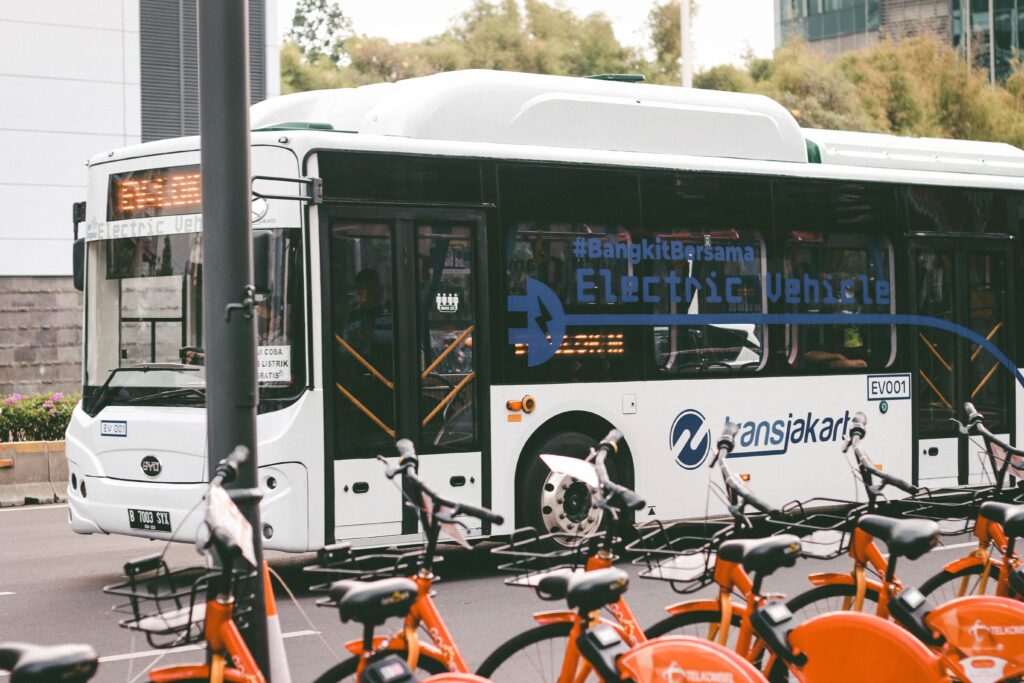 An electric bus parked next to rental bikes 