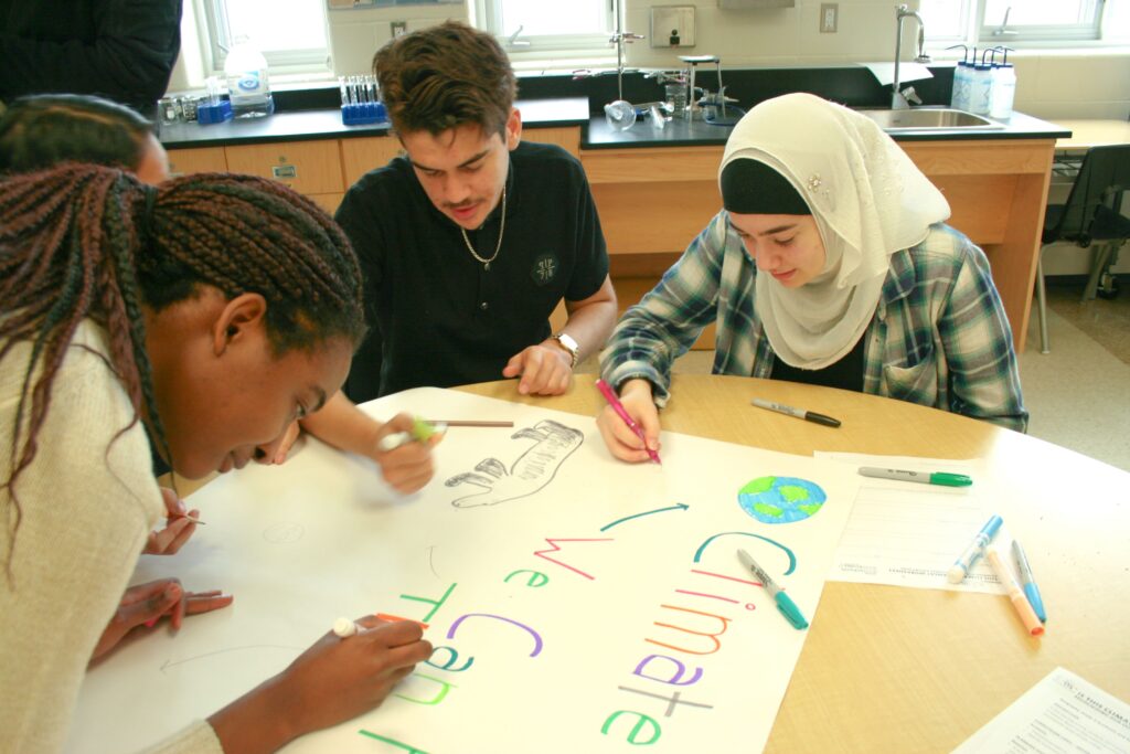 Trois élèves font une affiche pour l’action climatique 