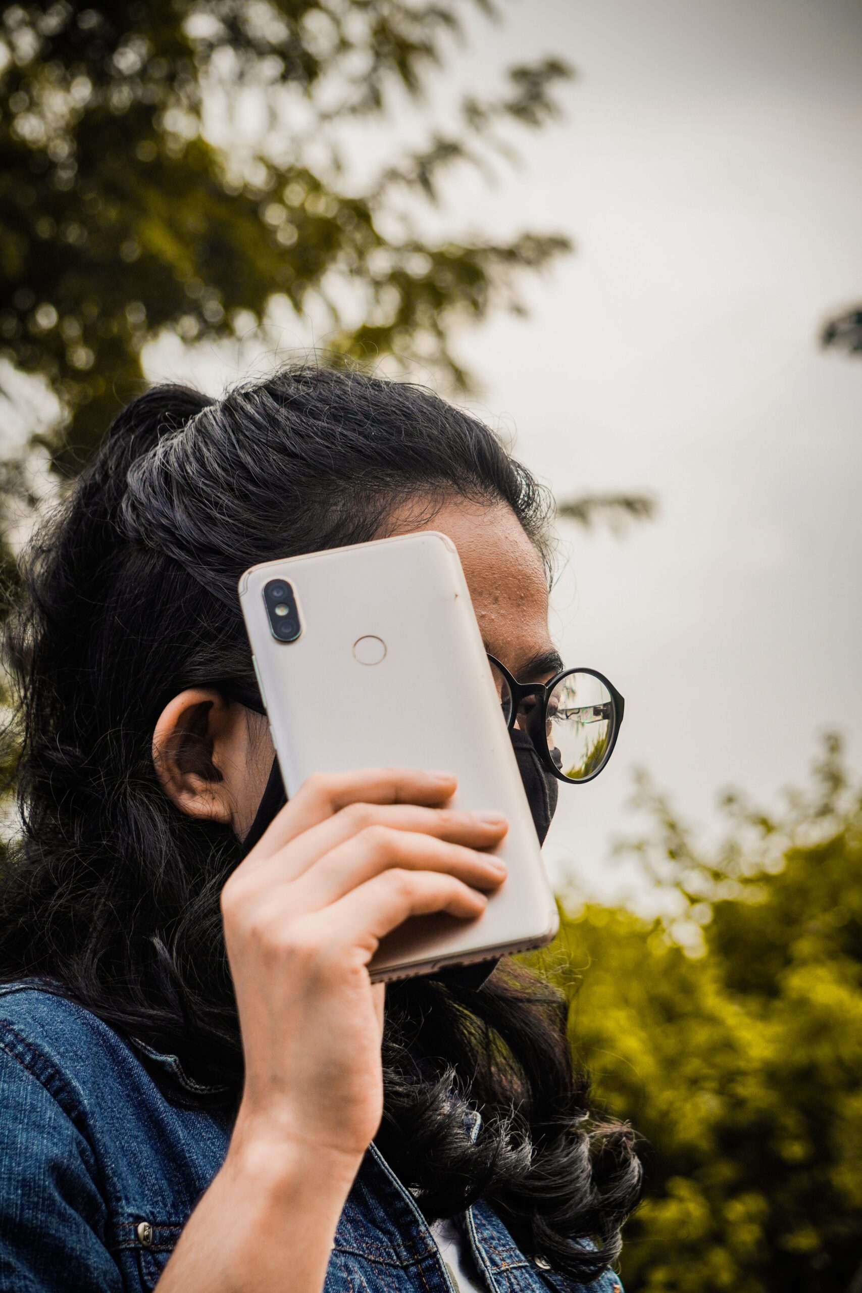 A woman hides her face behind a phone 