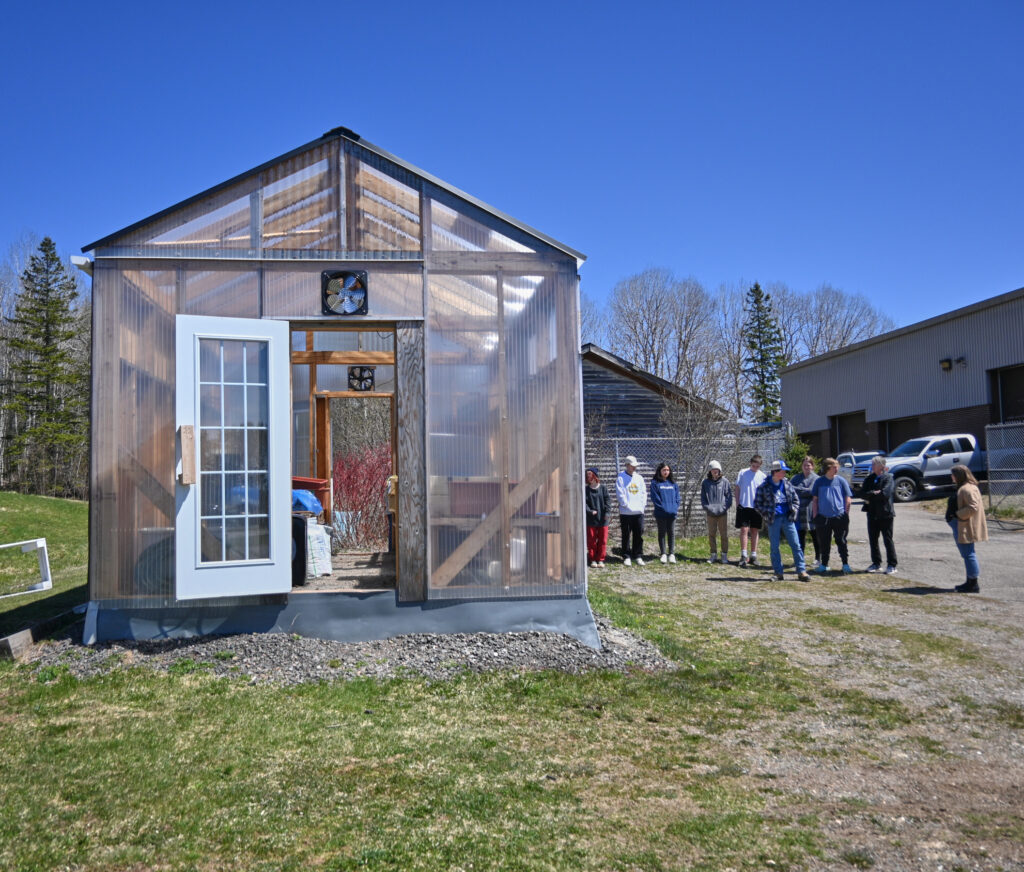 Students standing outside next to a greenhouse 