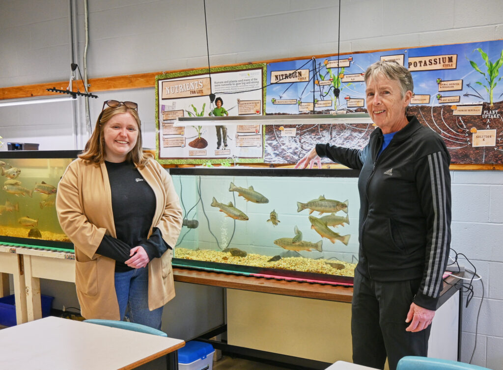 Ainslee and Ms. Giddens show the aquarium of trout to the camera 