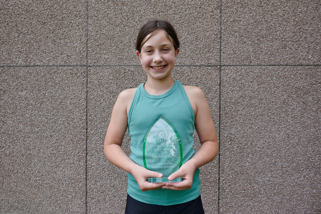 Ellie, holding her award, poses for a photo outside