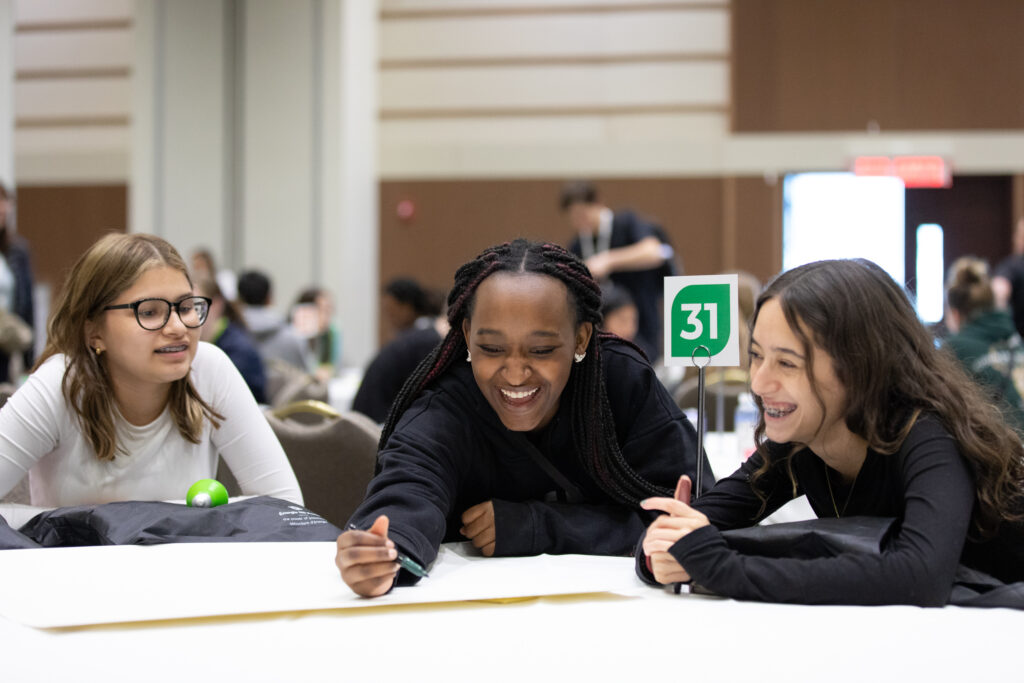 Three seated students brainstorming at the Empowering Tomorrow Conference 