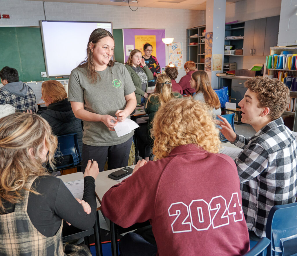 Une membre du personnel du Projet Gaia discute avec trois élèves dans une salle de classe 