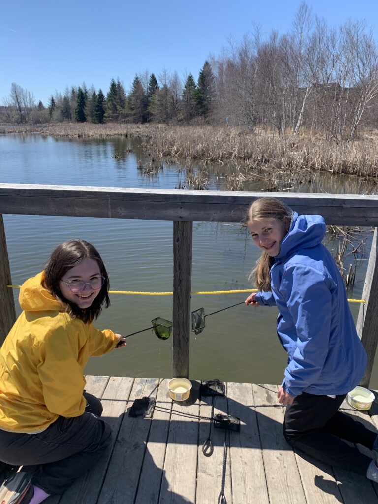 Two teen girls holding nets near a river