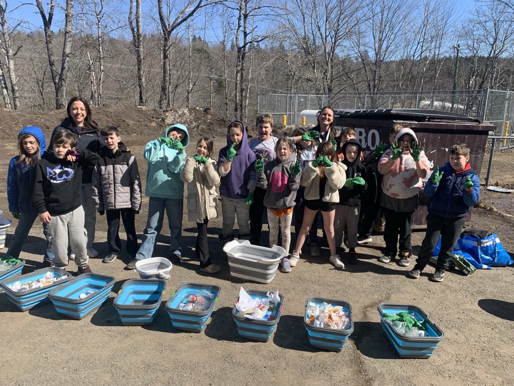 A class poses for a photo outside with their trash tracker waste sorting bins 