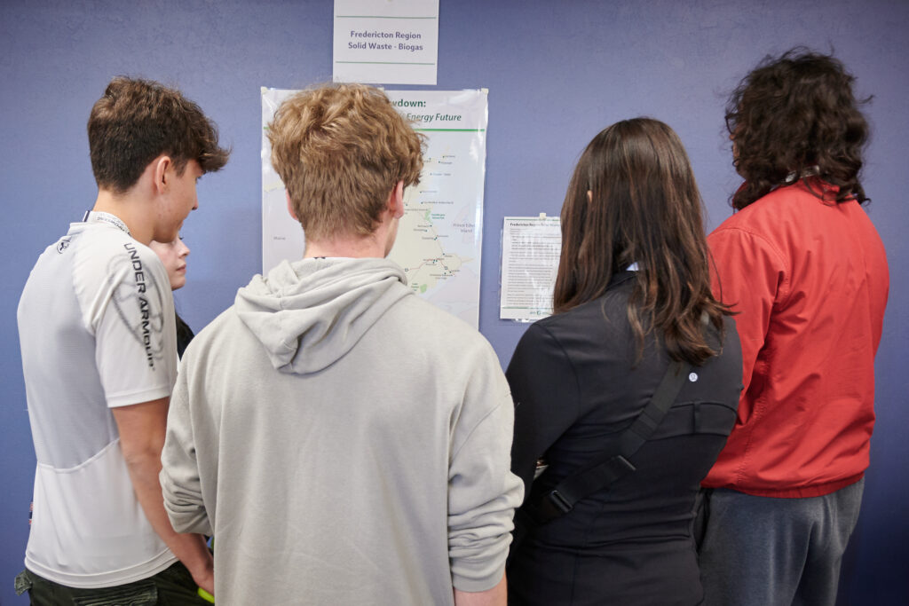 Four students look at a New Brunswick energy map on a wall 
