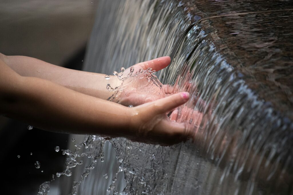 Hands catch water that is flowing of a ledge