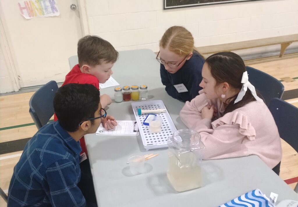 Four students gather around a water testing kit