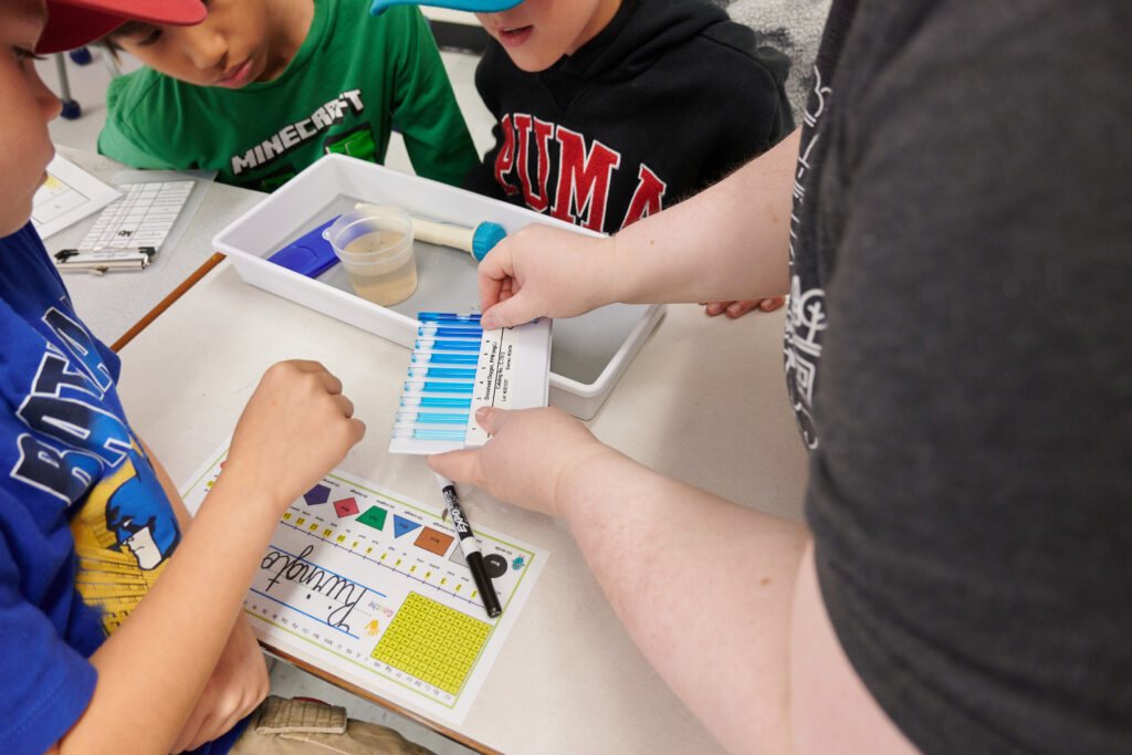 A Gaia Project staff member reviews a water sample with students