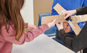 A photo of three students building a wind turbine from cardboard
